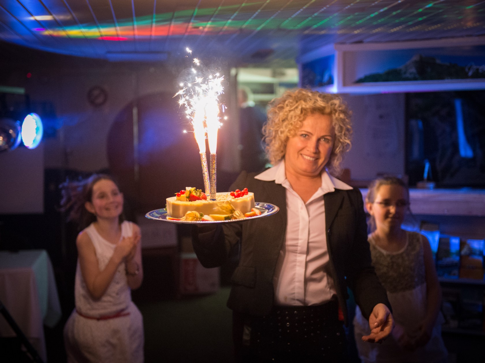 a person standing in front of a cake with lit candles